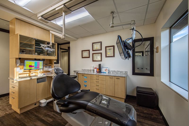 Treatment room with a modern dental chair, overhead light and a window